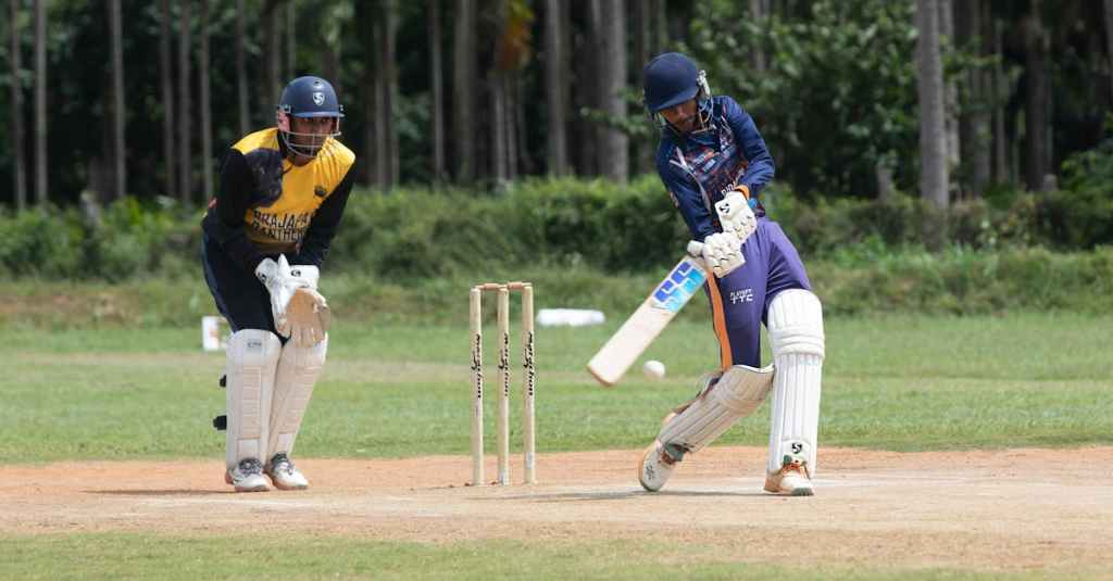 Two cricketers playing an intense match outdoors on a sunny day.